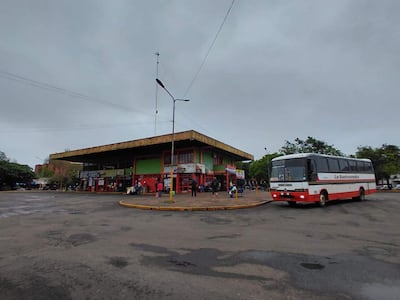 Ambiente urbano lluvioso con estructura de dos niveles y autobús de 'La Sanconia' estacionado.