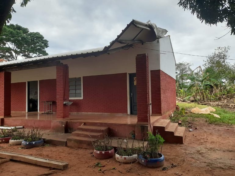 Casa de un piso con techo parcialmente dañado por tormenta en un área rural de Caaguazú, rodeada de vegetación.