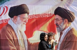 Varios iraníes pasan junto a una valla publicitaria que representa al difunto líder supremo iraní, el ayatolá Alí Jamenei (izq.), y a su hijo, el líder supremo iraní, el ayatolá Mojtaba Jamenei (der.), en Teherán, Irán, el 23 de abril de 2026.
