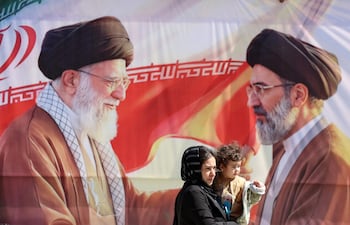 Varios iraníes pasan junto a una valla publicitaria que representa al difunto líder supremo iraní, el ayatolá Alí Jamenei (izq.), y a su hijo, el líder supremo iraní, el ayatolá Mojtaba Jamenei (der.), en Teherán, Irán, el 23 de abril de 2026.