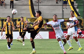 El defensor aurinegro Sebastián Zaracho saca ventaja hacia la pelota a Gaona Lugo. Más atrás, Roque, el autor del gol de la Academia.