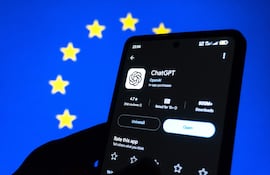 Teléfono móvil en primer plano con pantalla mostrando la aplicación ChatGPT, rodeado de un fondo azul con estrellas amarillas.