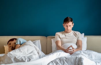 Un hombre y una mujer en la cama pensativos.
