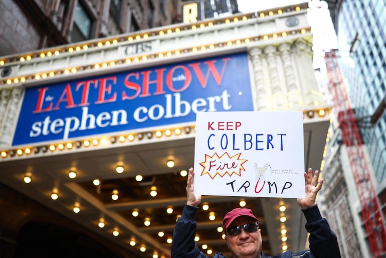 Un hombre sostiene un cartel que dice "Mantengan a Colbert, despidan a Trump" frente al teatro Ed Sullivan en Nueva York. (Photo by CHARLY TRIBALLEAU / AFP)