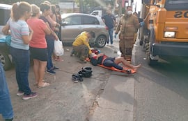 El motociclista, que fue embestido por el automóvil de color gris que está detrás de él, es atendido por los bomberos.
