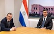 Santiago Peña y Carlos Carvallo Spalding sentados en una mesa, ambos en trajes oscuros y corbatas, con expresiones tranquilas.