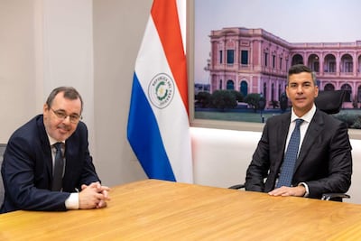 Santiago Peña y Carlos Carvallo Spalding sentados en una mesa, ambos en trajes oscuros y corbatas, con expresiones tranquilas.