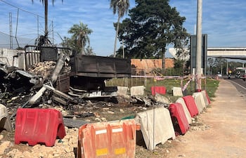 Camión volcado en la carretera rodeado de bloques de cemento en un área de construcción, sin personas visibles.