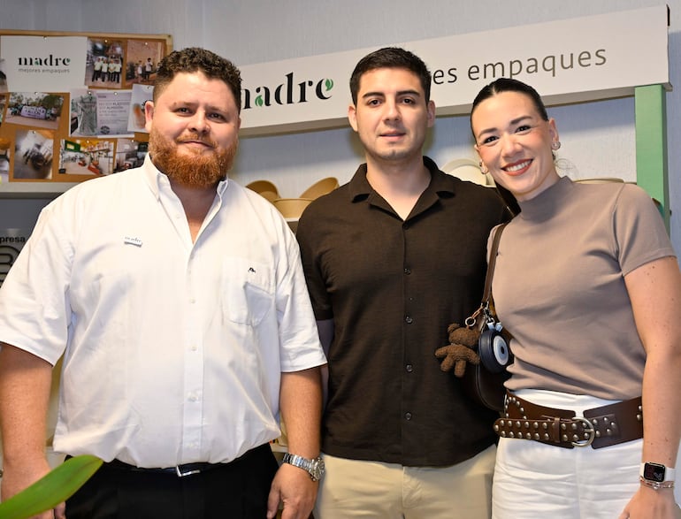 Hombre de barba rojiza con camisa blanca, hombre de cabello corto en camisa negra y mujer con blusa beige sonríen en un ambiente amigable.
