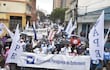 Manifestantes con paraguas y pancartas en apoyo a la Asociación Paraguaya de Enfermería, en un ambiente lluvioso.