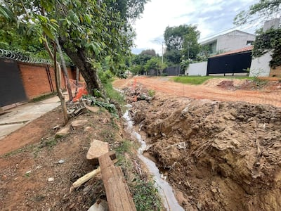 Terreno con zanja en construcción y muro de ladrillo rojo en un barrio en desarrollo.