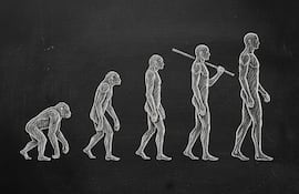 La imagen muestra la evolución humana representada como una secuencia de cinco figuras, dibujadas con tiza blanca sobre un fondo oscuro que se asemeja a una pizarra. Imagen generada con IA.