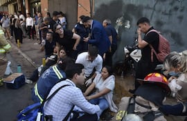 Mujer cubierta con manta blanca recibe asistencia de paramédicos en la calle General Díaz, rodeada de personas preocupadas.