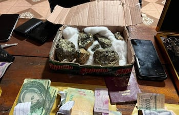 Entorno interior con caja de cartón, pasaporte, billetes y teléfonos móviles, indicando operación de seguridad en curso.