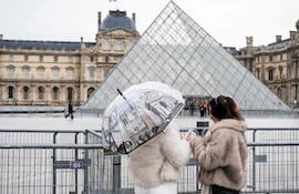 Fotografía de archivo: turistas permanecen junto a las vallas que bloquean la plaza donde se encuentra la Pirámide del Louvre, diseñada por el arquitecto sino-estadounidense Ieoh Ming Pei, mientras el Museo del Louvre permanece cerrado debido a una huelga en París, el 12 de enero de 2026.