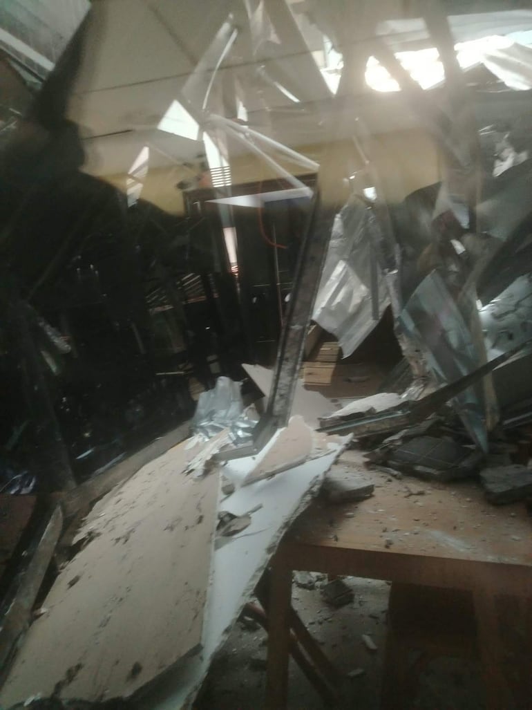 Espacio interior del Congreso en ruinas, con escombros y estructuras metálicas caídas. Luz entra irregularmente por el techo dañado.