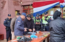 Uniformados observan herramientas sobre mesa de madera, en un entorno de intervención policial en Itapúa.