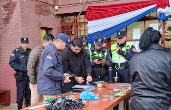 Uniformados observan herramientas sobre mesa de madera, en un entorno de intervención policial en Itapúa.