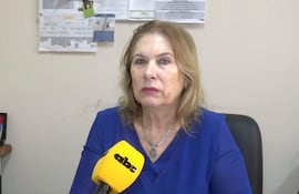 Teresa Sosa con blusa azul, mirando a la cámara en una oficina con documentos en la pared.