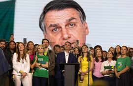 El senador Flávio Bolsonaro (c) reacciona durante la transmisión de un video de su padre, el expresidente Jair Bolsonaro enviando un mensaje de apoyo, el pasado sábado en la convención nacional del Partido Liberal (PL) en Sao Paulo (Brasil).