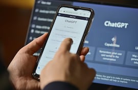 Mano sosteniendo un teléfono móvil que muestra la interfaz de ChatGPT en un fondo oscuro.