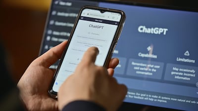 Mano sosteniendo un teléfono móvil que muestra la interfaz de ChatGPT en un fondo oscuro.