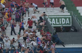 Hinchas de Cerro Porteño se enfrentan a policías antidisturbios ayer domingo en el estadio Defensores del Chaco.