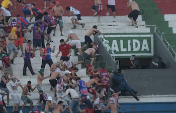Hinchas de Cerro Porteño se enfrentan a policías antidisturbios ayer domingo en el estadio Defensores del Chaco.