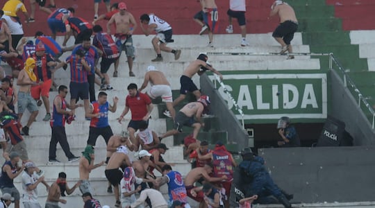 Hinchas de Cerro Porteño se enfrentan a policías antidisturbios ayer domingo en el estadio Defensores del Chaco.