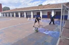 El estudiante José Figueredo y los voluntarios de "Levanta Escuelas" pintan la deteriorada cancha del Colegio Nacional Ignacio A. Pane.