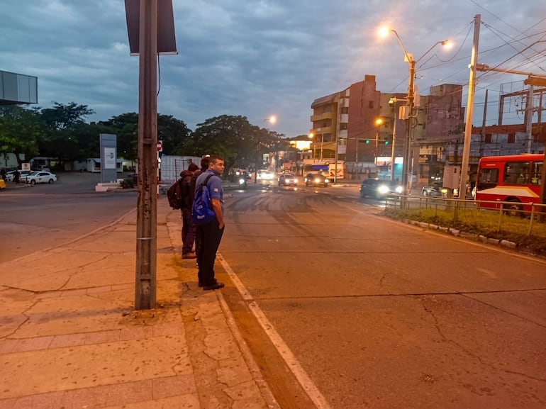 Hombre de pie esperando la llegada de un ómnibus de transporte público.