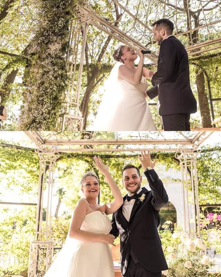 Sergio Irala en traje negro sonríe junto a su pareja vestida de blanco, ambos levantan las manos celebrando su boda en un gazebo floral.