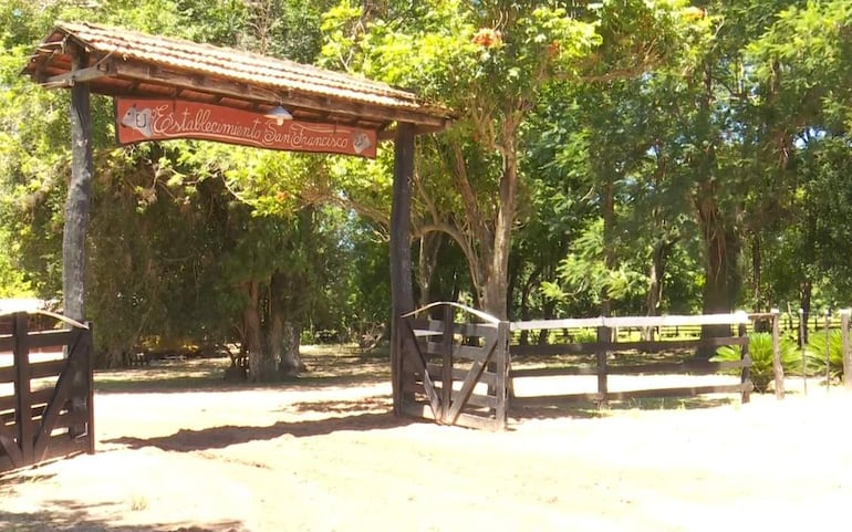 Arco de madera con inscripción 'Establecimiento San Francisco', rodeado de frondosos árboles y vegetación.