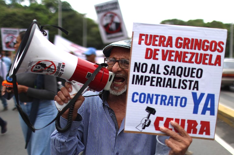 Un hombre sostiene un cartel durante una marcha contra el acuerdo petrolero entre Venezuela y Estados Unidos
