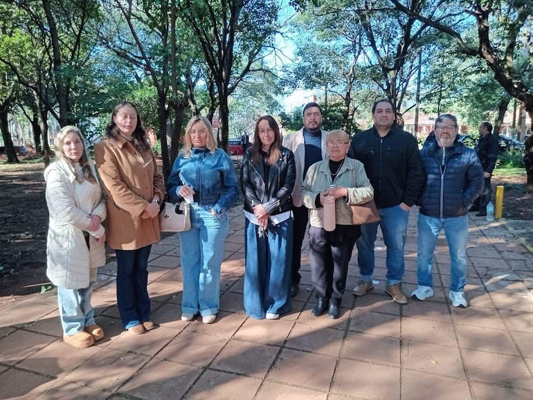 Grupo de ocho personas en un parque, posando. Mujeres y hombres con diversas vestimentas, rodeados de árboles.