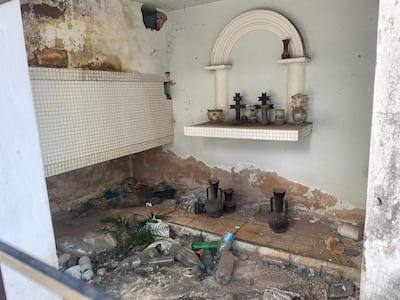 Ambiente deteriorado en Cementerio de la Recoleta, con repisa de jarras y basura en el piso, sin personas presentes.
