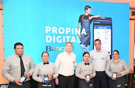 Seis personas, cuatro mujeres y dos hombres, posan frente a una pantalla con el logo de Bancard, todos sonrientes y con dispositivos móviles.