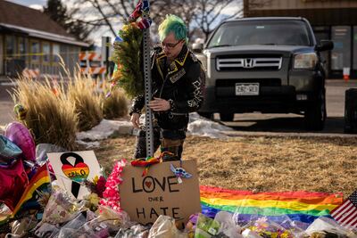 Una persona ata una cinta recordatoria en un improvisado altar erigido a las víctimas del tiroteo en el Club Q, de la comunidad LGTBI, en Colorado, Estados Unidos, (Foto de Archivo).