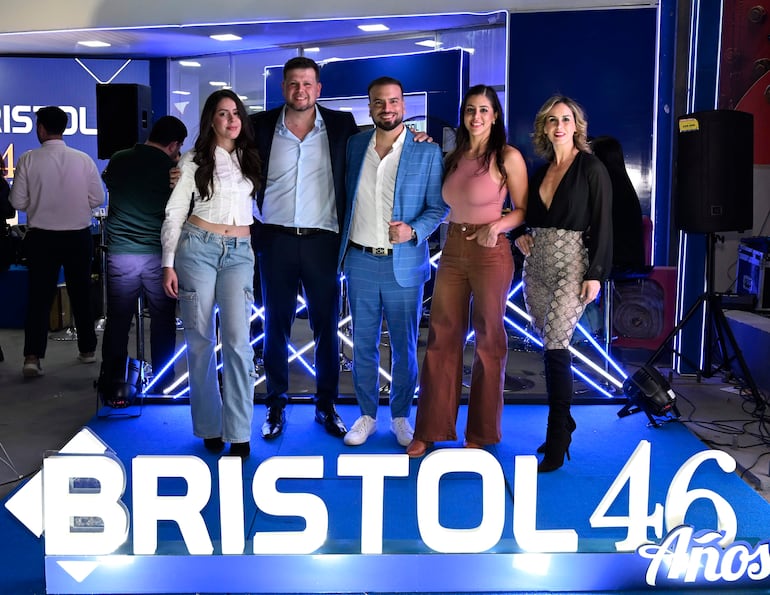 Diego Chamorro en traje azul con camisa blanca sonríe junto a cuatro mujeres elegantes en ambiente festivo.