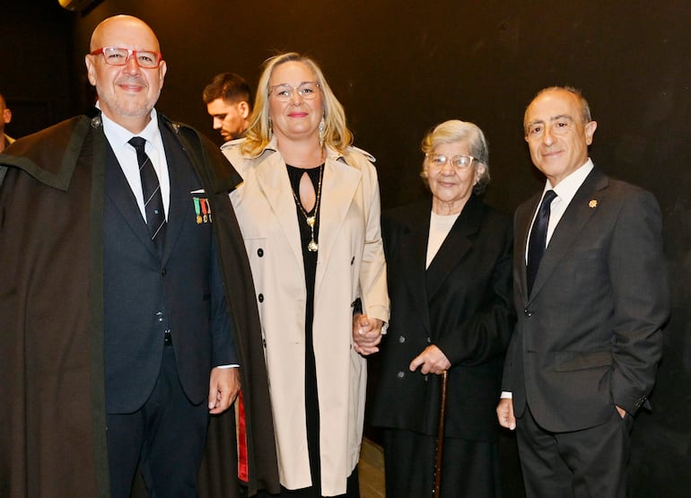 Cuatro personas sonriendo en el museo: un hombre con chaqueta con insignias, una mujer con abrigo claro y una anciana con bastón.