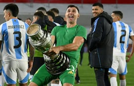 (FILES) Argentina's goalkeeper Emiliano Martinez gestures as he celebrates with a replica of the Copa America trophy after winning the 2026 FIFA World Cup South American qualifiers football match between Argentina and Chile at the Mas Monumental stadium in Buenos Aires on September 5, 2024. The Argentine Football Association (AFA) confirmed on September 28, 2024, in a statement that FIFA sanctioned goalkeeper Emiliano 'Dibu' Martinez with a two-match suspension for "offensive behavior" during the World Cup-2026 qualifiers against Chile and Colombia played in September. (Photo by Luis ROBAYO / AFP)