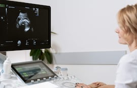 Obstetra observa una ecografía en consultorio.