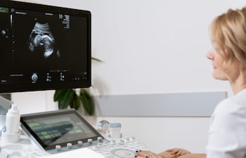 Obstetra observa una ecografía en consultorio.