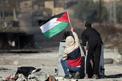 Jovenes ondean una bandera palestina durante un enfrentamiento con soldados israelíes durante una protesta en Ramala, Cisjordania, el miércoles.