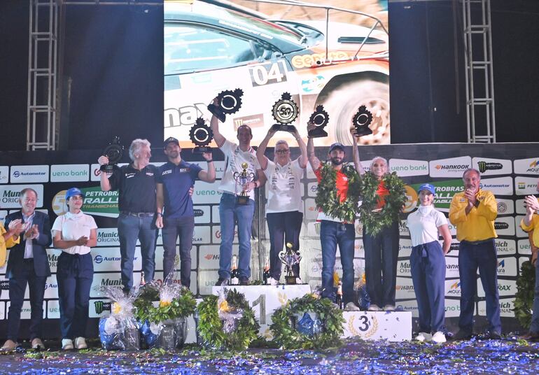 Gustavo Saba Rodríguez, acompañado de su madre Mirtha (centro), eleva en alto el trofeo de ganador de la clasificación general del TCR50. Fau Zaldívar (izq.) y Agustín Alonso también fueron protagonistas.