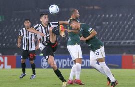 El atacante de Libertad Gustavo Ángel Aguilar eleva el pie izquierdo buscando disputar el esférico con Jesús Castillo.