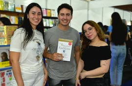 Mujeres sonrientes acompañan a un hombre que sostiene 'Las 4 Disciplinas de la Ejecución' en un entorno de feria del libro.