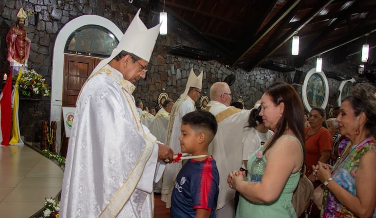 Monseñor Pedro Collar bendice, en nombre de San Blas, el cuello de un niño durante una de las misas del novenario.