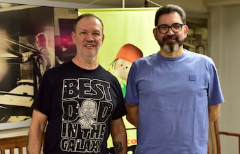 Tito Ibarrola en camiseta negra y Tony Apuril en camiseta azul posean juntos en una oficina. Ambos lucen tranquilos.