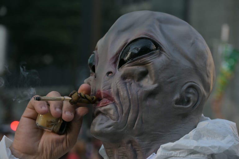 Un hombre enmascarado fuma marihuana durante una manifestación que exige su legalización en la Avenida Paulista de São Paulo, Brasil.